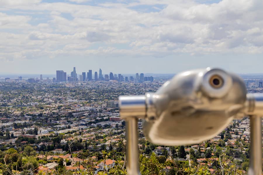 scenic view from Griffith Observatory overlooking Downtown Los Angeles with a coin-operated observation telescope in the foreground.