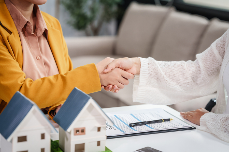 Asian businesswoman discusses home purchase contracts with clients at her desk